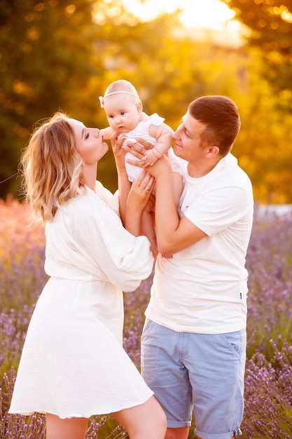 Beautiful portrait of a young family with baby in lavender field. Family love and value concept.