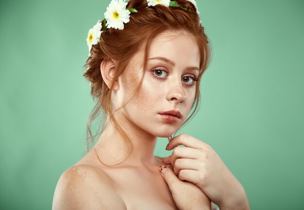 Beautiful positive redheaded girl with a chamomile crown on her head