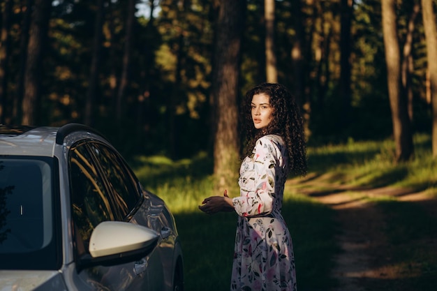 A beautiful positive woman in yellow clothes with a road map near the car at a picnic on an autumn day The concept of the road freedom rest travel