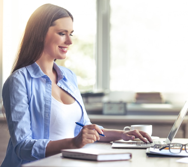 Beautiful pregnant business woman is using a laptop.