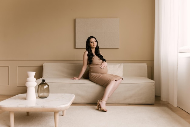 Beautiful pregnant girl with curls in a dress in a bright studio with a stylish interior the concept of a happy pregnancy and family