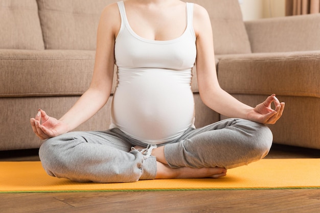 Beautiful pregnant woman doing yoga at home Pregnancy Yoga and Fitness concept at coronavirus time