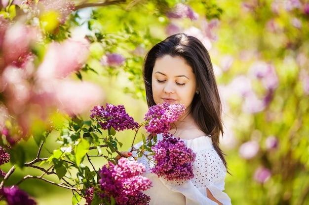 Beautiful pregnant woman enjoying lilac garden