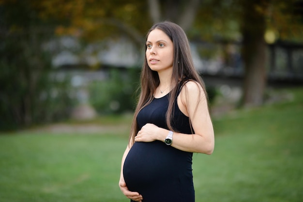 Beautiful pregnant woman relaxing outside in the park Portrait of a happy and proud pregnant woman