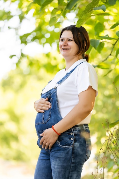 Beautiful pregnant woman relaxing outside in the park