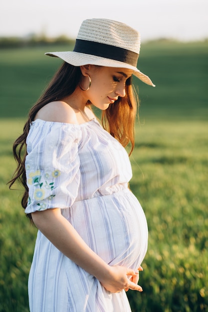 Beautiful pregnant woman in the spring nature field on sunset