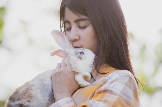 Beautiful pretty portrait of young Asian woman person with cute rabbit in pet and animal care concept happy female holding bunny at nature outdoor field with friendship easter concept