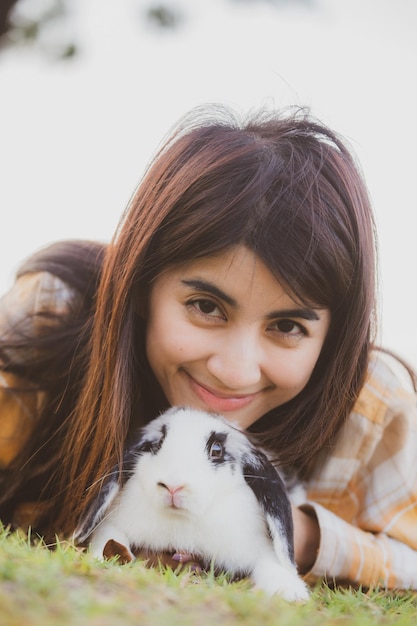 Beautiful pretty portrait of young Asian woman person with cute rabbit in pet and animal care concept happy female holding bunny at nature outdoor field with friendship easter concept