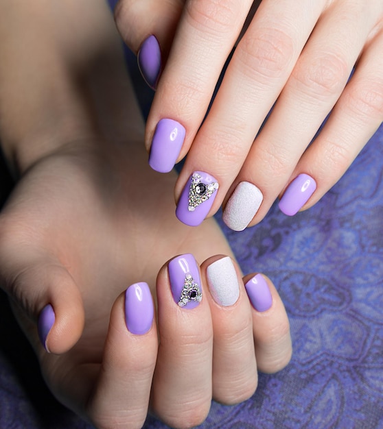 Beautiful purple manicure with  crystals on female hand. Close-up. Picture taken in the studio