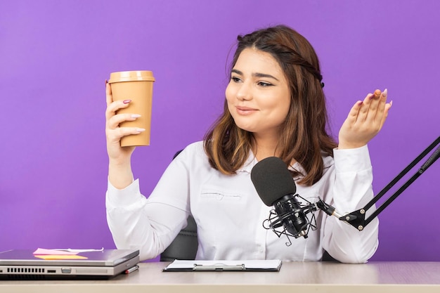 Beautiful radio presenter holding her coffee and smiling High quality photo