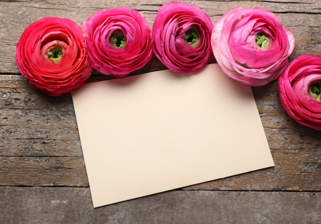 Beautiful ranunculus flowers and card on wooden background