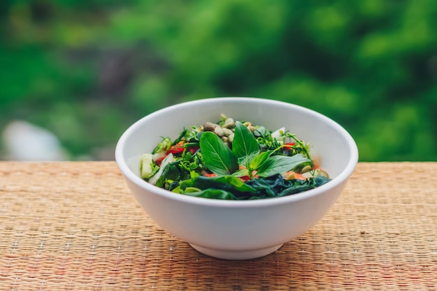 Beautiful raw vegan salad from green leaves mix vegetables in white plate Cooking recipe Blended tomato carrot cauliflower cut parsley cilantro dill greenery cucumber basil pumpkin seed seaweed