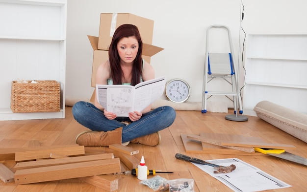 Beautiful red-haired female reading a manual before do-it-yourself