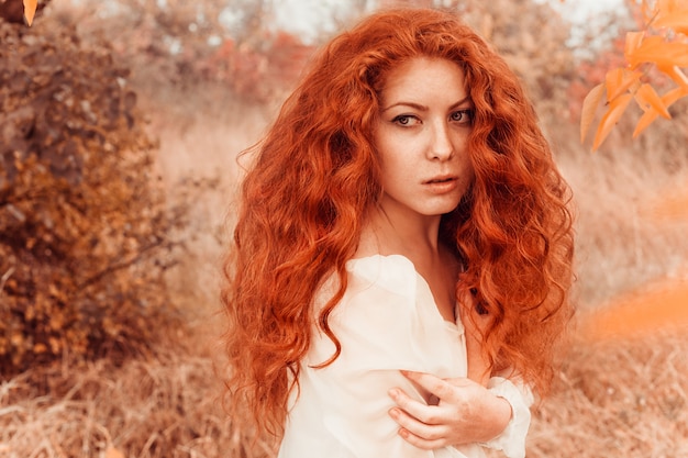 Beautiful red-haired young woman in autumn forest