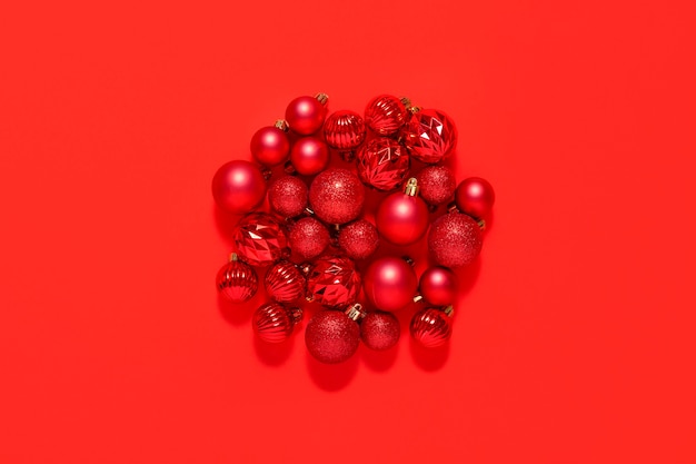 Beautiful red small decorative balls are scattered on a red background. Top view, flat lay.