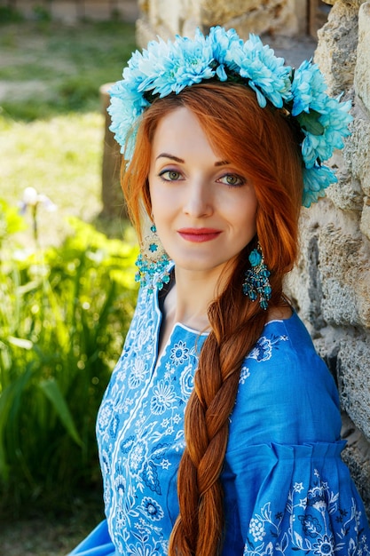 Beautiful redhaired girl in a blue dress Ukrainian with a wreath on her head