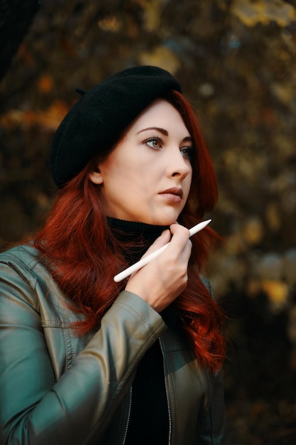 Beautiful redhaired woman in the park brooding woman in a beret and leather jacket man with a pen de...