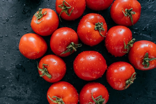 Beautiful ripe fresh red tomatoes growned in greenhouse Water drops on heirloom vegetables isolated on dark background Agriculture