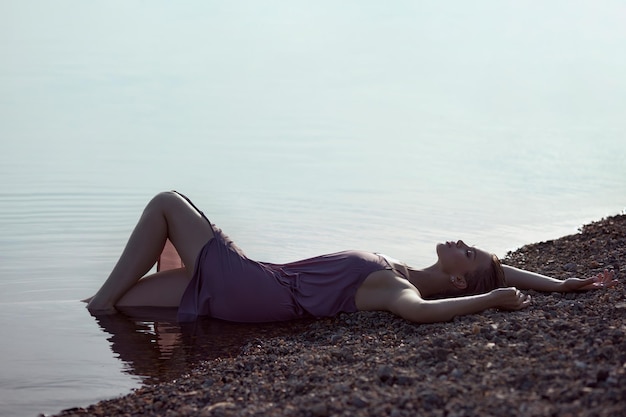 Beautiful romantic young woman is resting on the lake Perfect body a woman in the water at sunset