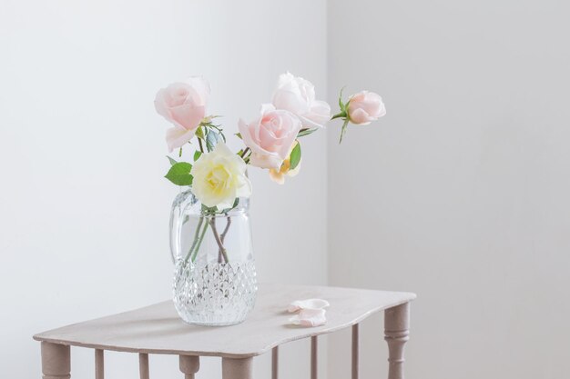 Beautiful roses in glass jug on white background