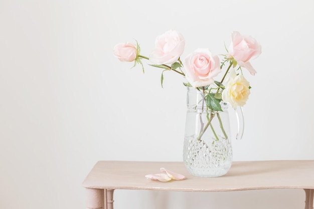 Beautiful roses in glass jug on white background