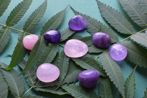 Beautiful round amethyst stones and rose quartz with a green branch on a green background