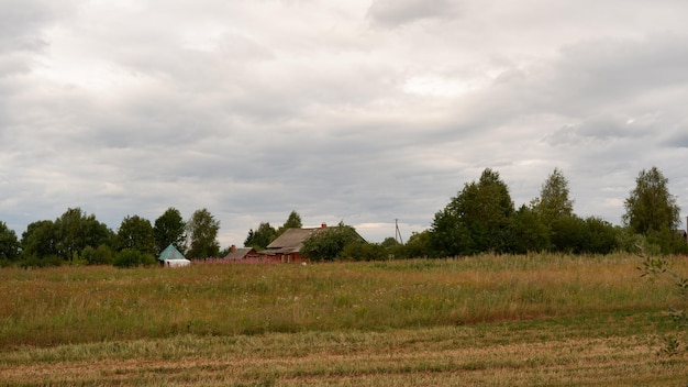 Beautiful rustic summer landscape with old wooden houses and hay in the field