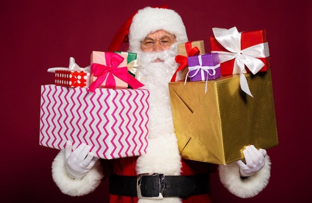 Beautiful Santa Claus shows many gift boxes in hands