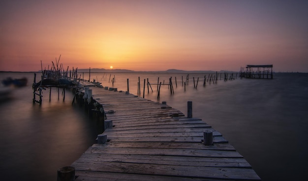 Beautiful scenery of a wooden dock in a port in Carrasqueira, Comporta, Portugal at sunset