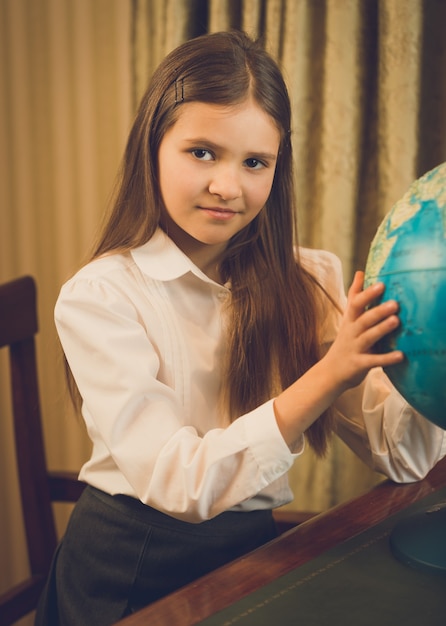 Beautiful schoolgirl posing at cabinet with Earth globe