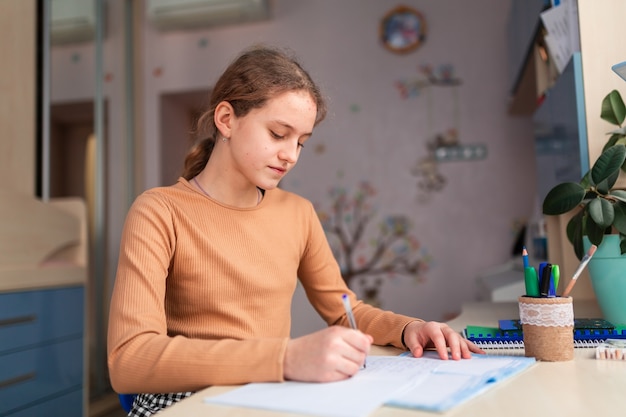 Beautiful schoolgirl studying at home doing school homework