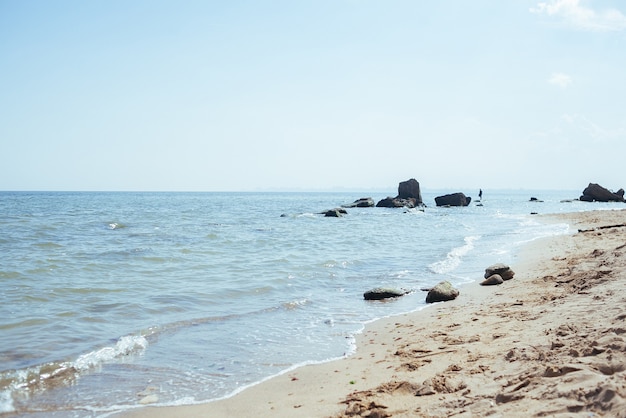 Beautiful sea at noon in summer, clear water, sand beach. silent waves are illuminated by the midday sun.