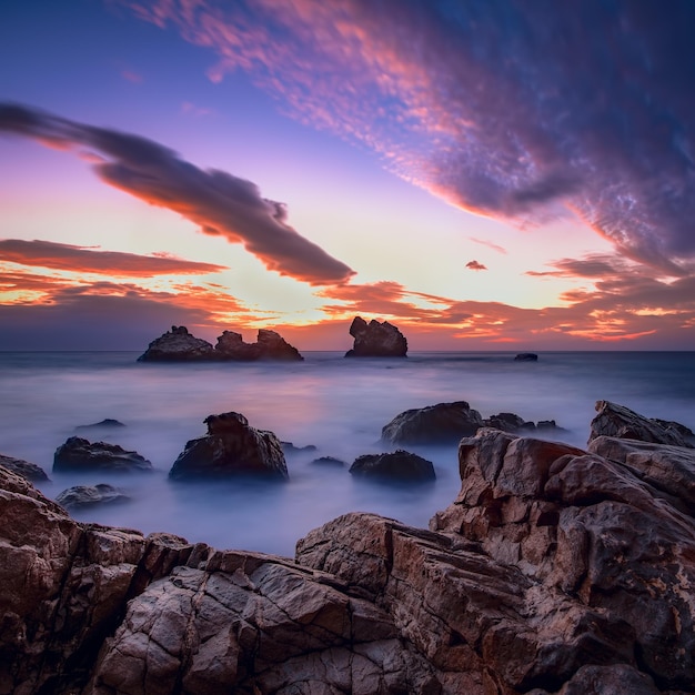 Beautiful seascape at dawn with clouds in the sky There are textured stones in foreground fragments