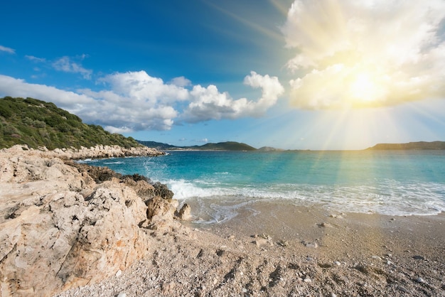 Beautiful seascape green rocky coast sandy beach and blue water in the sunlight