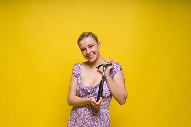 Beautiful seductive female holding hammer isolated on yellow and red