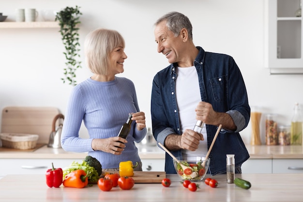 Beautiful senior spouses making healthy dinner together at home