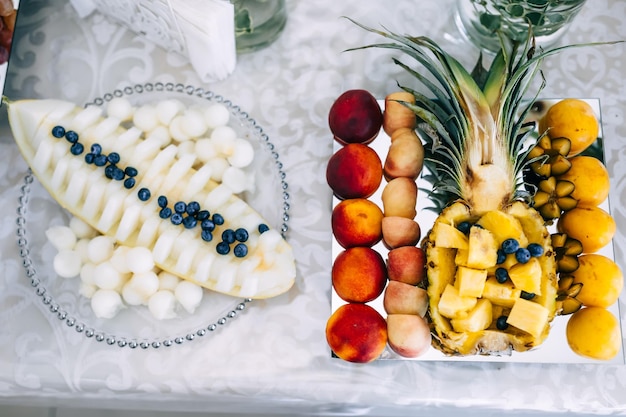 Beautiful serving of sliced fruits Fruit table with melon pineapple peach berries