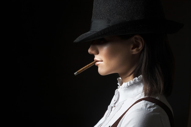 Beautiful sexy brunette woman in hat smoking cigarette