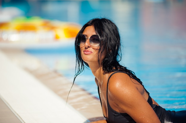 Beautiful and sexy girl in a swimwear relaxing near swimming pool