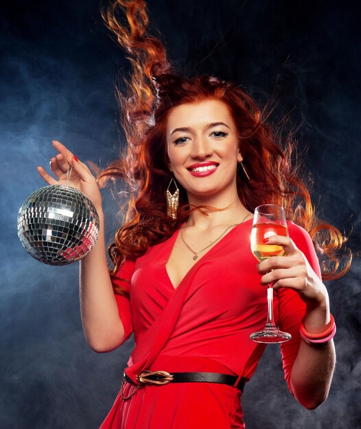 Beautiful sexy redhair woman with a glass of white wine and disco ball