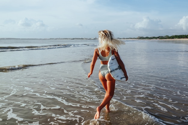 Beautiful sexy surfer girl on the beach at sunset