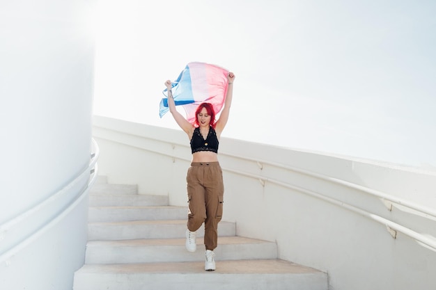 Beautiful shot of a female waving red and blue flag over her head while coming downstairs