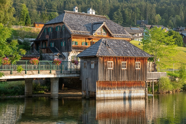 Beautiful shot of wooden houses on a bridge alongside the river and forests in Grundlsee, Austria