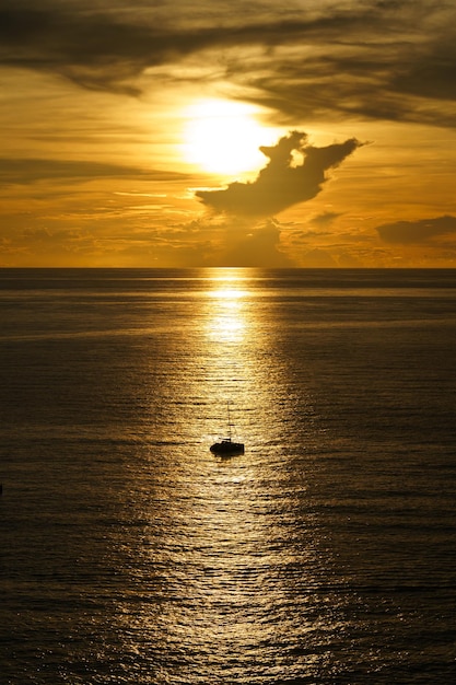 Beautiful silhouette of sailboat on sunset at sea with reflection. Summer sun golden hour hot sunset sky.