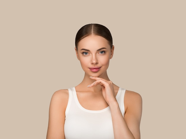 Beautiful skin face woman natural make up healthy skin touching her face. Color background. Brown