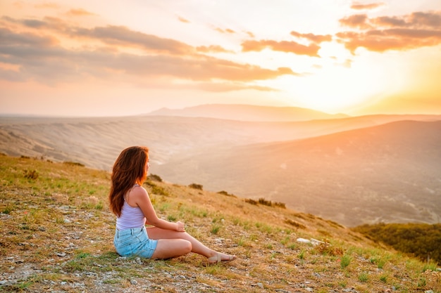 Beautiful slender woman on top of a mountain at sunset Amazing landscape