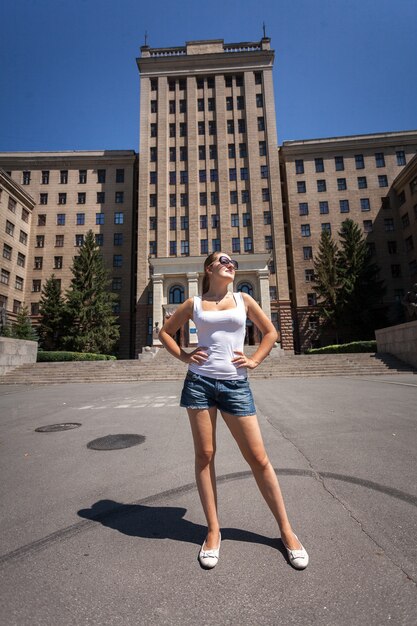 Beautiful slim woman standing on street against high building