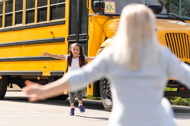 Beautiful small girl with mother near school