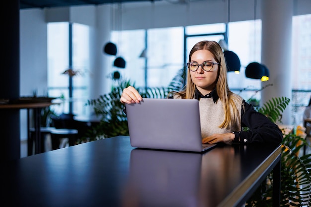 Beautiful smart charming attractive elegant owner of a large company is holding an online meeting with international business partners, she is sitting at the table in her workplace