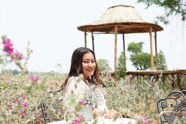 Beautiful smile Asian woman sit and relax in vintage flower garden